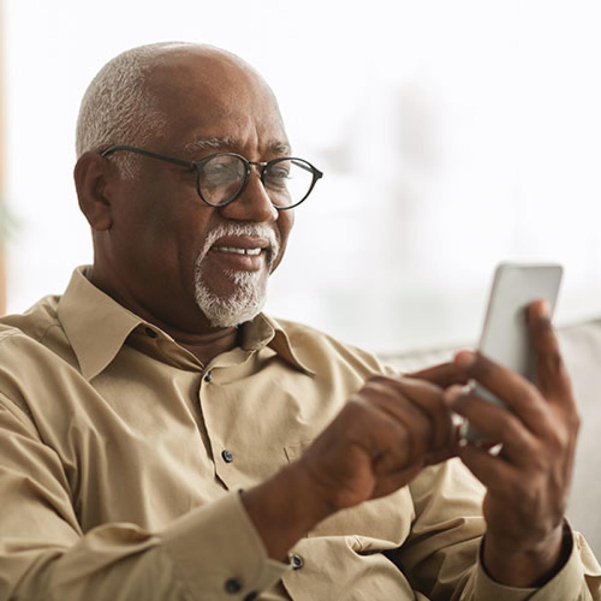 A man smiles while he scrolls on his phone.
