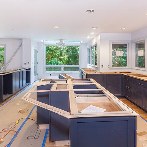 Kitchen construction with blue, unfinished cabinets.