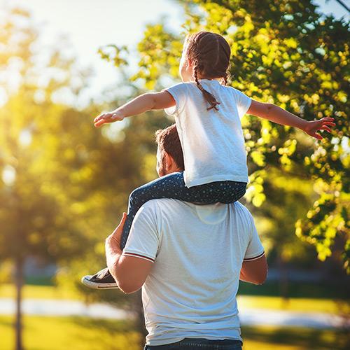 Daughter on her dad's shoulder outside.
