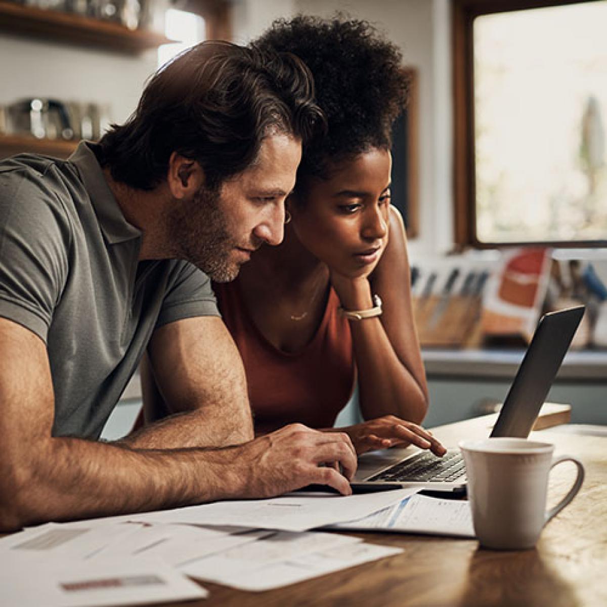 A couple looking at a laptop in their kitchen.