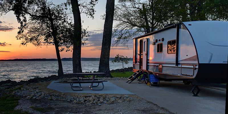 Parked RV near an outdoor table and body of water.&nbsp;
