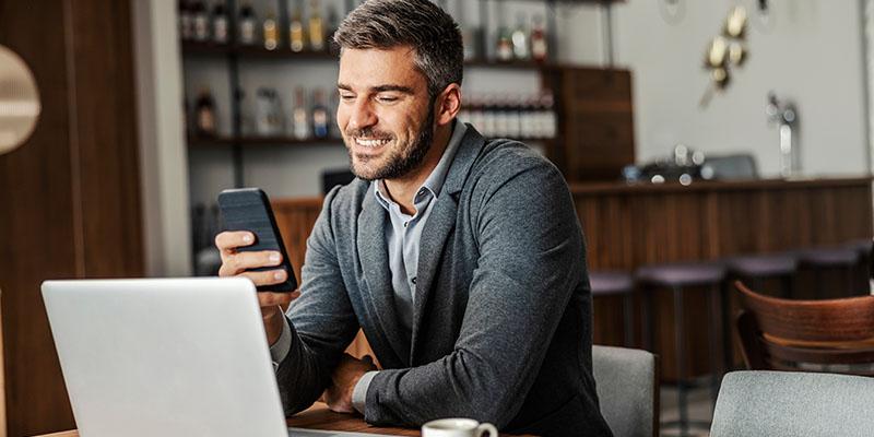Man looking at his phone and laptop.