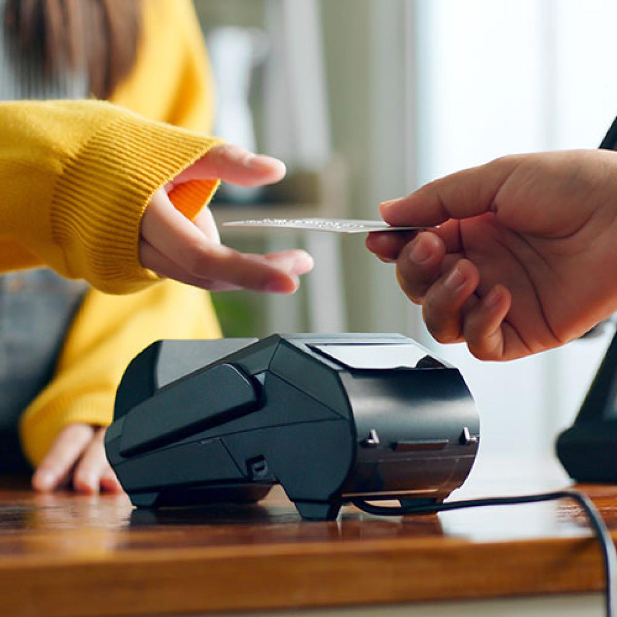 A person&nbsp;hands a credit card to another person.