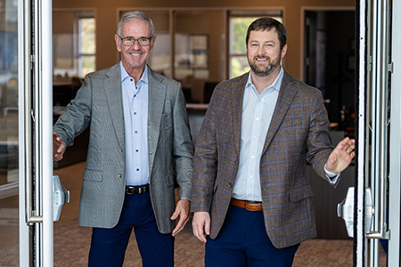 Two men in suits welcoming into bank